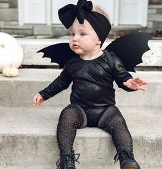 a baby dressed up as a bat sitting on steps