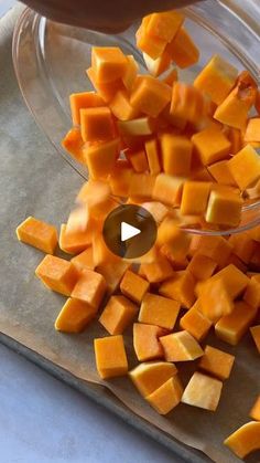 someone is cutting up pieces of buttered pumpkin on a cutting board with a knife