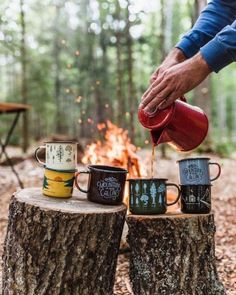 a person pouring coffee into mugs sitting on top of a tree stump