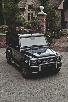 a black mercedes g - class parked in front of a house