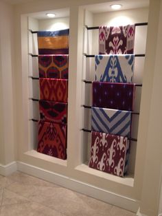 several different colored towels are on display in a room with white walls and tile flooring