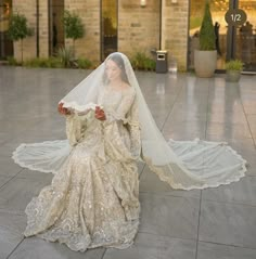 a woman in a wedding dress is sitting on the floor with her veil over her head