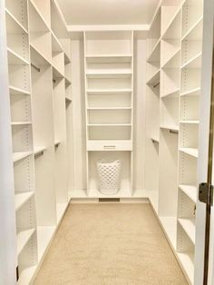 an empty walk in closet with white shelving and beige carpeting on the floor