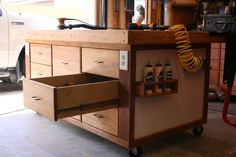 a workbench with drawers and tools on it in front of a white truck