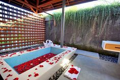 an outdoor bathtub with red flowers on the floor