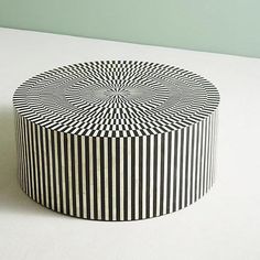 a black and white striped box sitting on top of a table next to a green wall