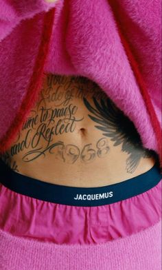 the back of a woman with tattoos on her stomach and in pink shirt under a blanket