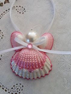 a pink and white shell with a pearl in it's center on a lace doily