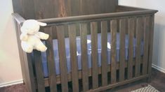 a teddy bear sitting on top of a wooden crib