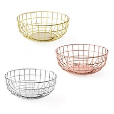 three metal bowls sitting side by side on a white surface, each with different colors