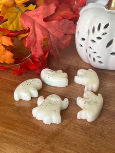 white candles are sitting on a table next to fall leaves