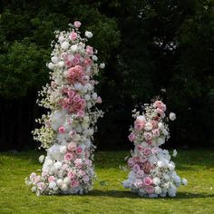 two tall white and pink flowers on top of each other in front of some trees