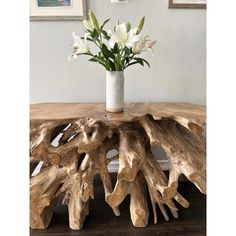 a vase filled with white flowers sitting on top of a wooden table covered in driftwood