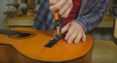 a man is using a pair of scissors to cut a guitar