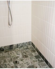 a tiled bathroom with a shower head and hand held shower faucet in the corner