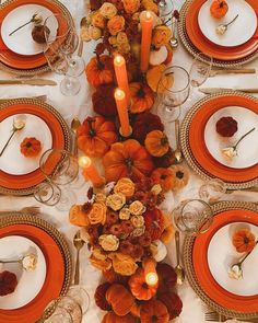 the table is set with orange plates and candles