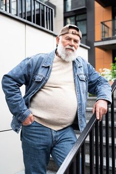 an older man standing on the steps with his hands in his pockets and looking at the camera