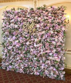 a wall covered in pink flowers with the words bride and groom written on it's side