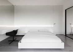 a white bed sitting in the middle of a bedroom next to a desk and mirror