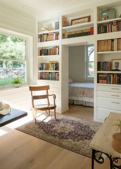 a living room filled with furniture and bookshelves next to a bed in a bedroom