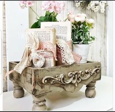 an old wooden box with books and flowers in it sitting on a table next to a wreath