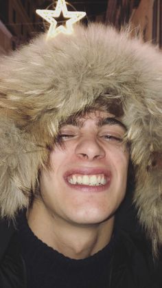 a young man wearing a furry hat with a star on it's top and his eyes closed