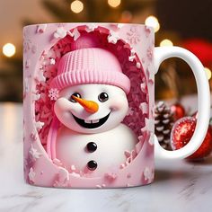 a frosty snowman mug with a pink hat and scarf on it next to christmas decorations