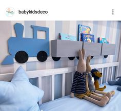 two stuffed animals sitting on top of a bed next to a wall mounted book shelf