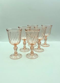 six wine goblets are lined up on a white surface