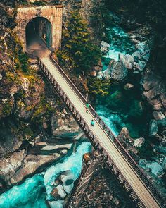 an aerial view of a bridge over a river with blue water and trees in the background