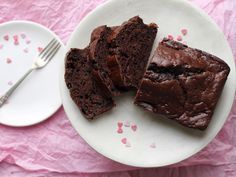 two pieces of chocolate cake on a plate with a fork next to it and one piece is cut in half