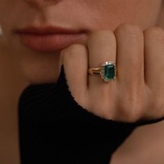 a close up of a person wearing a ring with a green stone on it's finger