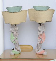 two lamps sitting on top of a wooden table next to each other, one with a lamp shade over it's head