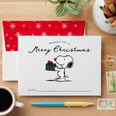 a christmas card with a cartoon character holding a present on top of it next to a cup of coffee