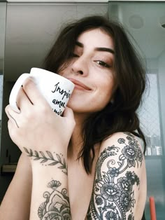 a woman with tattoos holding a coffee cup