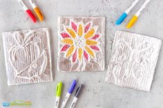 some crayons and markers are sitting on the table next to two small cards