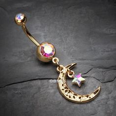 a gold plated belly button with a crescent moon and stars dangling from the side