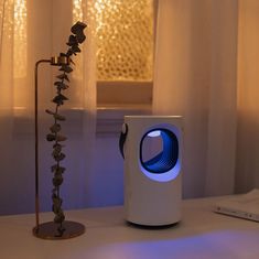 an electronic device sitting on top of a table next to a window with curtains in the background