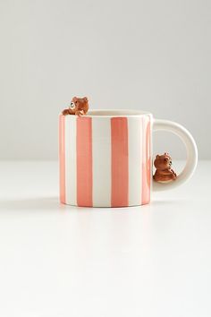 a coffee mug with two small bears on the inside, and one is pink and white stripes