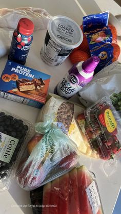 an assortment of fruits and vegetables on a white counter top with plastic wrap around them