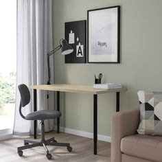 a desk with a chair, lamp and pictures on the wall in a living room