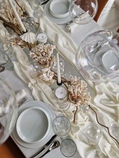 the table is set with white dishes and place settings