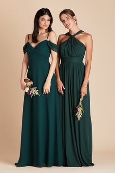 two women in long dresses standing next to each other, one wearing a green dress