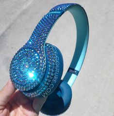 someone is holding up their headphones with blue crystals