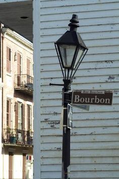 a lamp post with a street sign attached to it's side next to a building