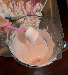 someone is mixing something in a bowl with marshmallows on the side and toothpicks sticking out of it