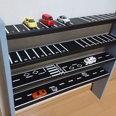 toy cars are lined up on top of a bookcase that is built into the wall