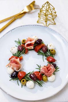 a white plate topped with olives, tomatoes and other food on top of it