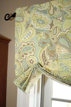 a window with a green and blue curtain hanging from it's valance next to a bed