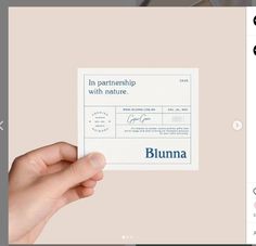 a person holding up a paper with the word bluuma on it in front of a computer screen